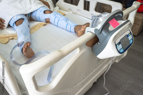 Close up unknown patient lying on hospital bed with Sequential Compression Device (SCD) on both legs after surgery