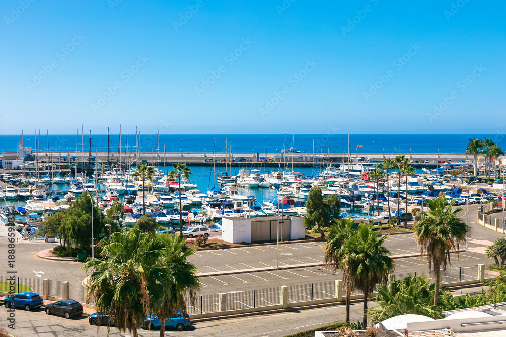 Fototapeta premium Busy waters of Puerto Rico in Gran Canaria, Spain. Overlooking a densely packed marina filled with numerous moored sailboats and motorboats