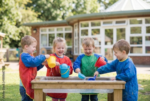 Children playing with water at outdoor activity table in a sunny nursery playground