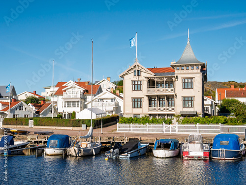 Small boats moored along harbour quay with historic wooden villa on Hamngatan in Marstrand, Bohuslän, west coast Sweden