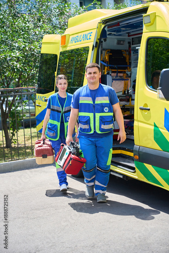 Two paramedics demonstrating AED beside ambulance