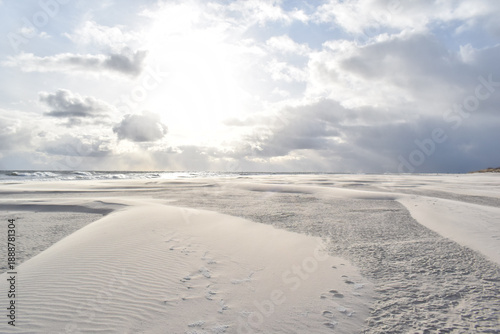 Dramatic stormy sky over an empty sandy beach with waves and dark clouds. Moody seascape landscape with strong wind, cold atmosphere and vast open space. Minimalist coastal scenery, solitude and natur