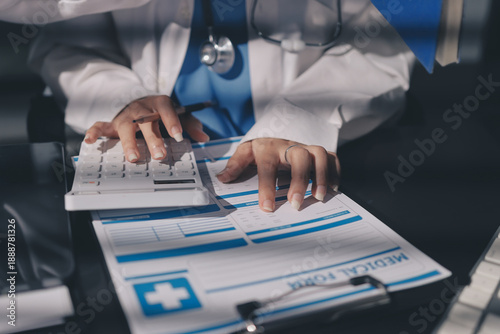 Two doctors and a female nurse meet at a table in the hospital, collaborating on medical tasks using laptops and computers
