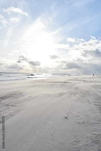 Dramatic stormy sky over an empty sandy beach with waves and dark clouds. Moody seascape landscape with strong wind, cold atmosphere and vast open space. Minimalist coastal scenery, solitude and natur