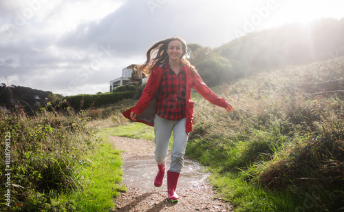 Valokuva Happy woman running on a muddy trail with puddles in sunlight