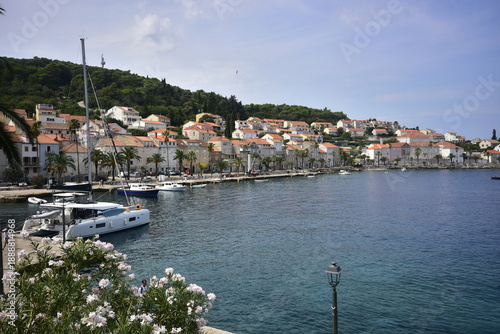 Idyllic Croatian harbor town with red roofs and palm trees