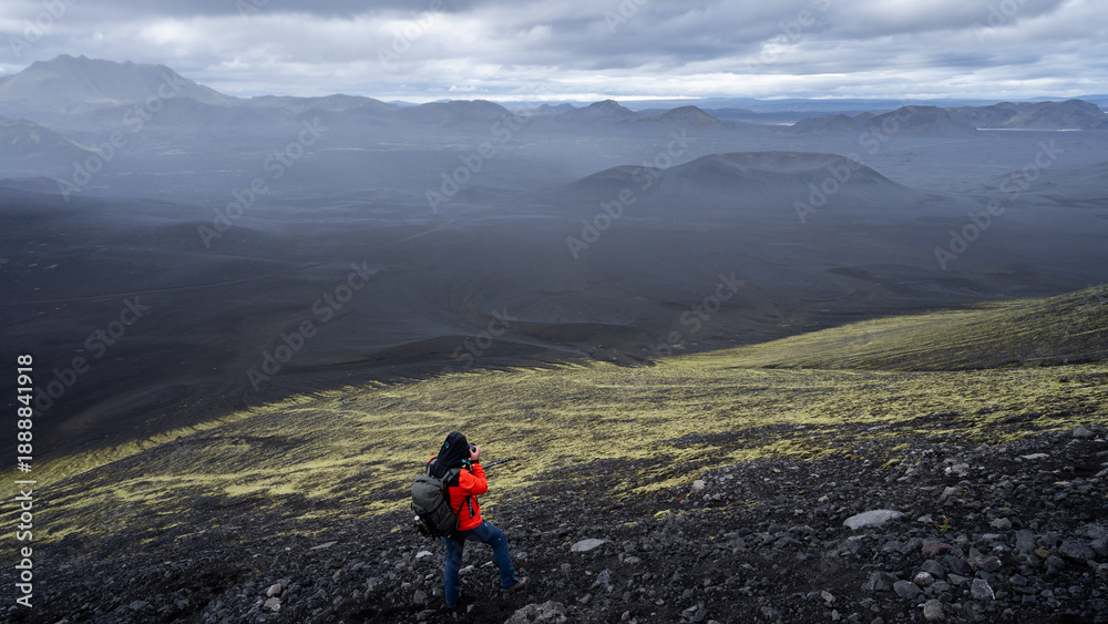 Obraz premium Hiker photographing vast desert like volcanic landscape covered by black sand, Highlands, Iceland
