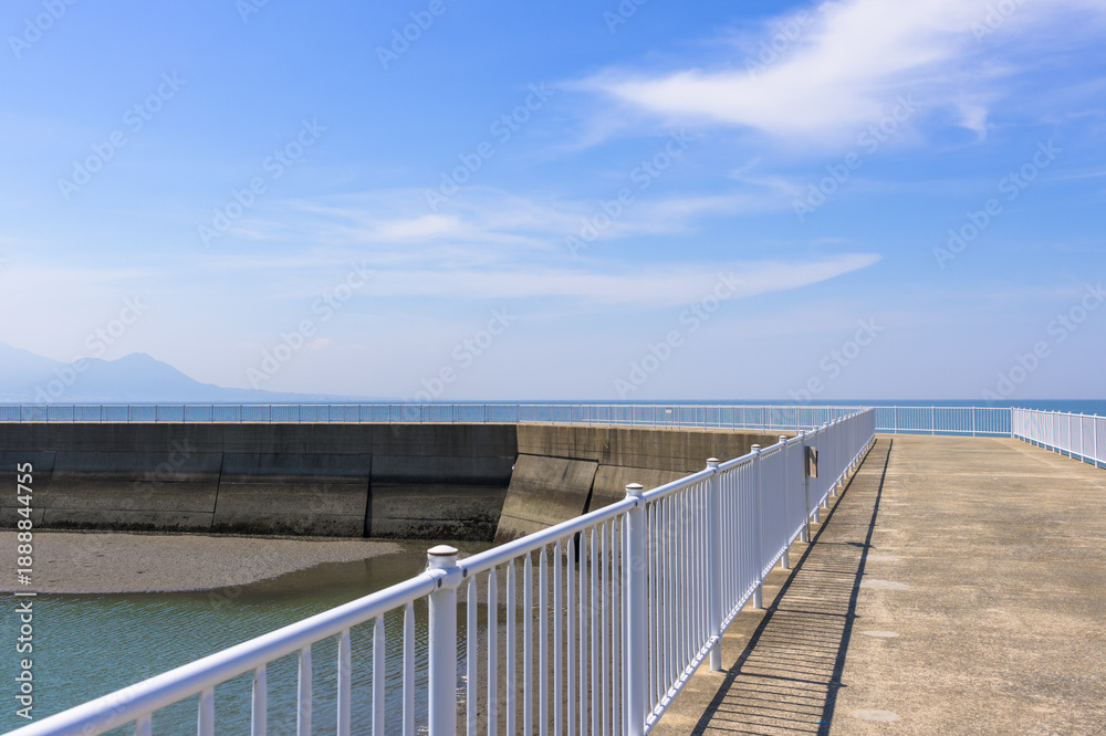 Obraz premium 青空を背景に 「潮風が運ぶ、防波堤から見える海と遊歩道」 宇土市観光スポット(宇土マリーナおこしき館) With a blue sky as a backdrop 