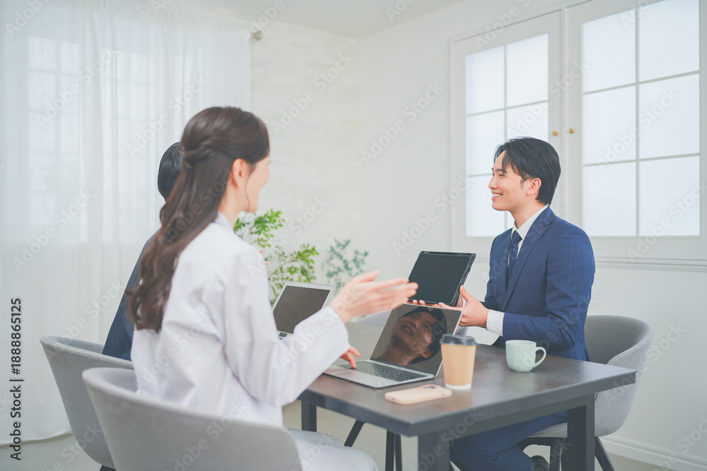 Obraz premium クリニックの会議室で打ち合わせをする若い医師とビジネスマン