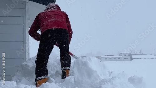 屋根から落ちた雪を寄せる作業をしている男性　豪雪　大雪　イメージ