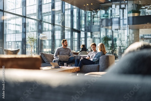 Young professionals collaborating in modern office lounge with laptops