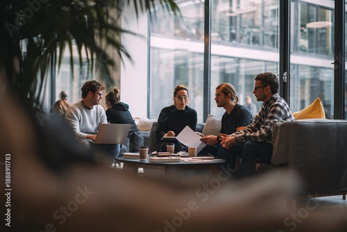 Team collaborating in modern office lounge with laptops and documents