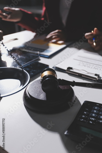 Judge gavel with Justice lawyers having team meeting at law firm in background. Notary with client in office