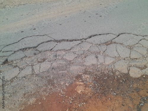 Cracks in the asphalt surface of the road due to repeated use by overloaded vehicles.