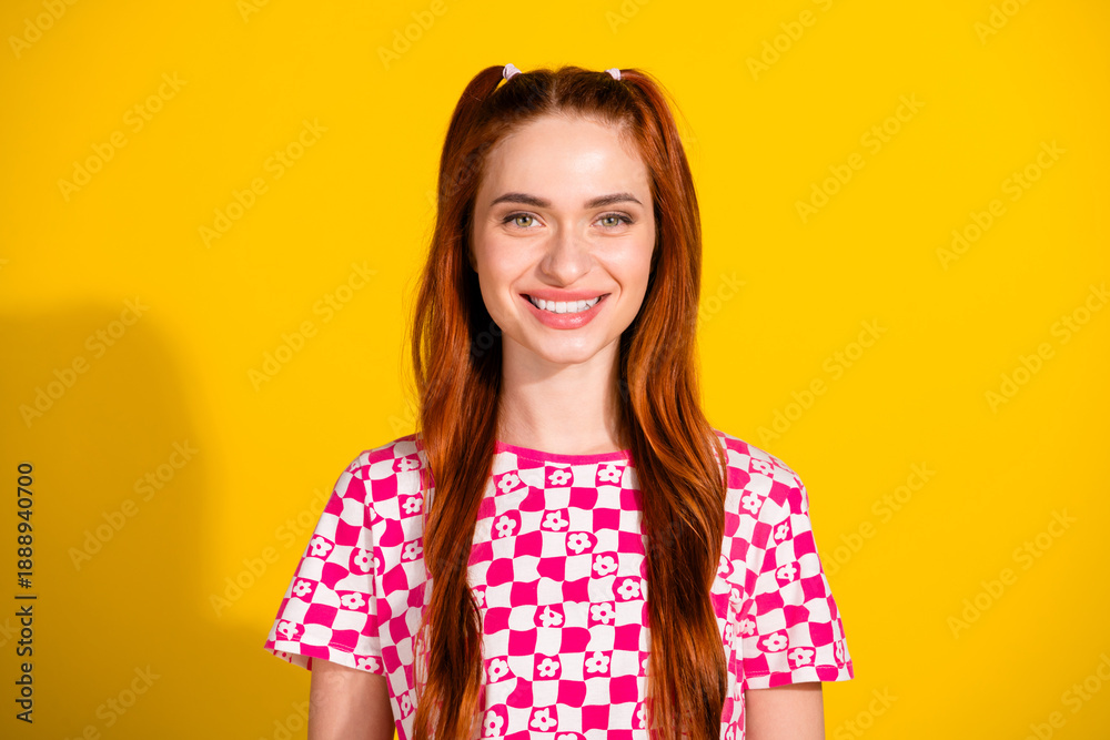 Obraz premium Young woman with red hair in checkered pink and white top smiling against yellow background lifestyle fashion portrait