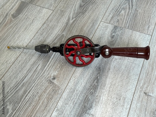 Vintage hand crank drill with iconic red gear and wooden handle, classic manual woodworking tool 