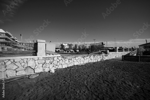 Foto Ostia, Rome, Italy - January 25, 2026, section of a travertine retaining wall in opus incertum with perspective view of a stretch of public beach near the Hakuna Matata kiosk