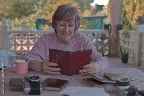 Mujer mayor sonriente mirando un álbum de fotos antiguo