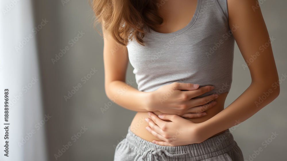 Naklejka premium Young Woman Holding Stomach in Pain, Abdominal Pain and Digestive Problem Concept, Female Health, Gastrointestinal Disorder, Menstrual Cramps, Medical and Healthcare Background