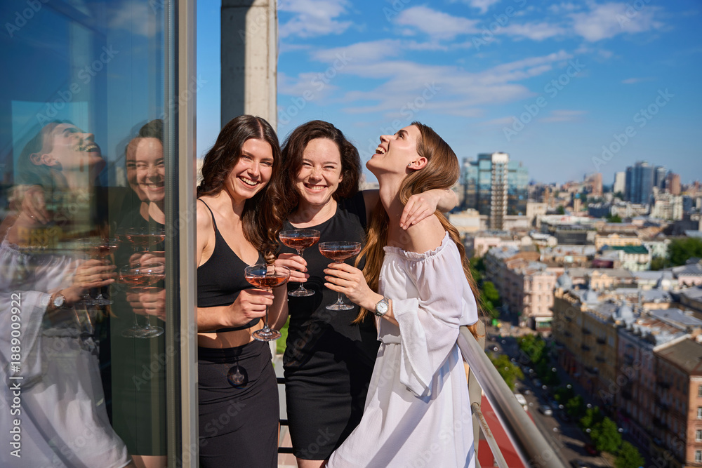 Naklejka premium Happy young women with glasses of champagne having party on terrace outdoors