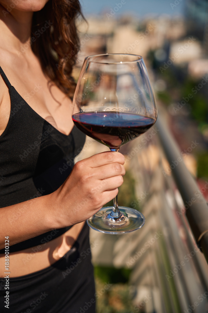 Fototapeta premium Close up of female hand holding glass with red wine on terrace outdoors