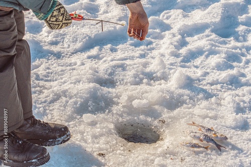 Konstfotografi Ice fishing with rod and reel beside a drilled hole on a frozen lake during wint
