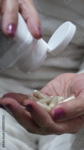 Close-up of a woman's hands pouring nutritional supplement pills from a white bottle