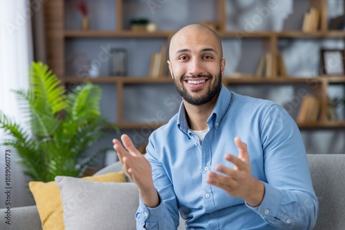 Photography Young bald man in blue shirt is smiling and actively gesturing while virtually c