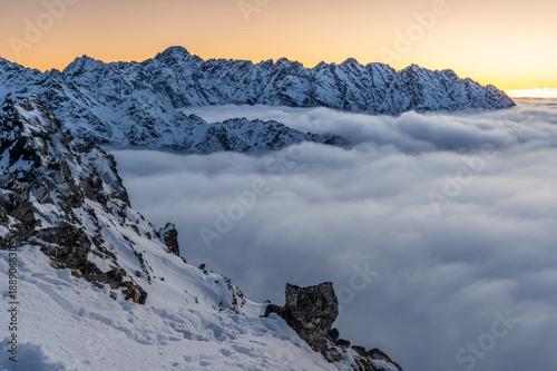 Winter sunset view of High Tatra mountains, with valleys filled by clouds, seen from Szpiglasowy Wierch to the Hruby Peak, Poland, Slovakia