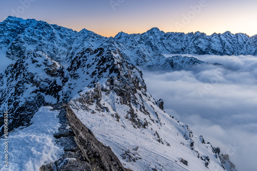 Winter sunset view of High Tatra mountains, with valleys filled by clouds, seen from Szpiglasowy Wierch to the Hruby Peak, Poland, Slovakia