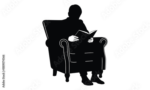 Silhouette of a man engrossed in reading a book while seated in a classic armchair