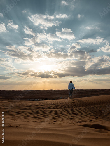 Woman walking alone in Wahiba Sands desert, Oman at golden hour