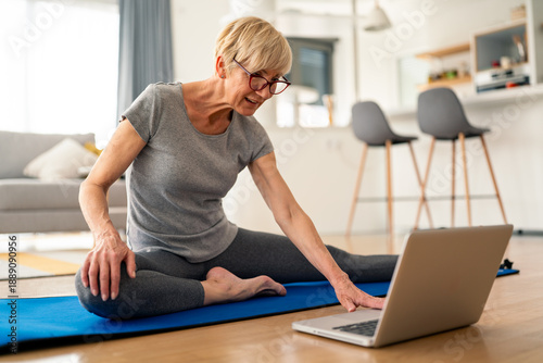 Slika na platnu Senior woman stretching and practicing yoga at home wearing casual gray outfit a