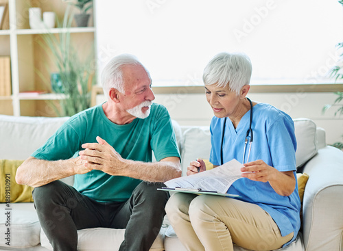 Portrait of a senior doctor or nurse caregiver talking consultation with senior man at home or nursing home