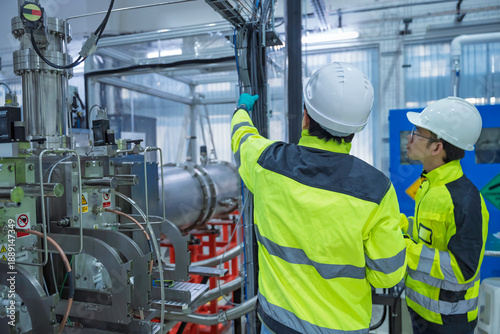 Fotografija Two professional Asian electrical technicians inspect complex wiring and control panels