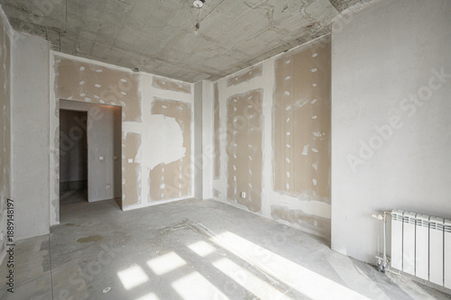 Принти на полотні Unfinished room with plastered walls, exposed concrete ceiling floor, radiator installed, doorway open, patchy drywall, awaiting final finishing touches