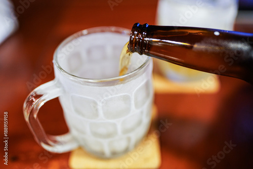 Pouring cold beer into frosty mug for refreshment