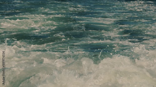 Close-up seething wake with foam and spray from boat motor. Turbulent flow from watercraft's engine on surface of sea. slow motion