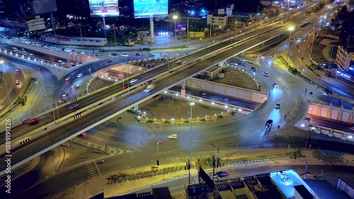 Drone view of nighttime car lanes, highway, and intersections in the city, city road, car lanes, expressway between buildings, traffic flow on city road, expressway and highway, traffic junction car