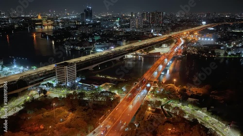 Drone view of nighttime car lanes, highway, and intersections in the city, city road, car lanes, expressway between buildings, traffic flow on city road, expressway and highway, traffic junction car