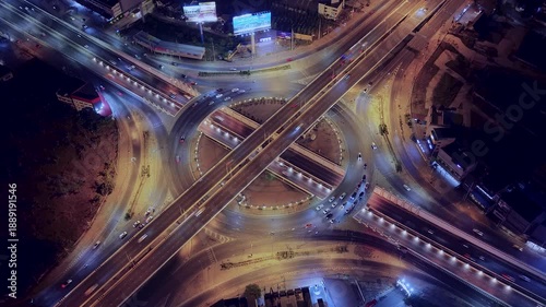 Drone view of nighttime car lanes, highway, and intersections in the city, city road, car lanes, expressway between buildings, traffic flow on city road, expressway and highway, traffic junction car