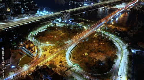 Drone view of nighttime car lanes, highway, and intersections in the city, city road, car lanes, expressway between buildings, traffic flow on city road, expressway and highway, traffic junction car