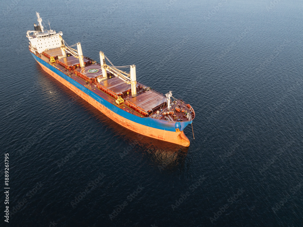 Fototapeta premium High angle aerial drone shot of an empty bulk carrier ship floating in the deep blue Baltic Sea water during winter