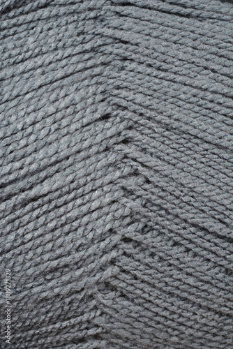 Close up macro view of dark gray knitting yarn showing detailed fiber structure and twisted threads arranged in a diagonal pattern