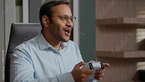 Canvas Print Funny lazy Indian Arabian business man playing joystick video game at office sca