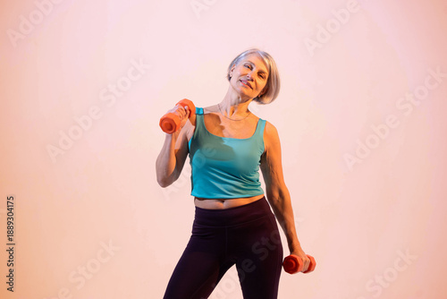 Foto Confident mature woman training with dumbbells in a modern gym