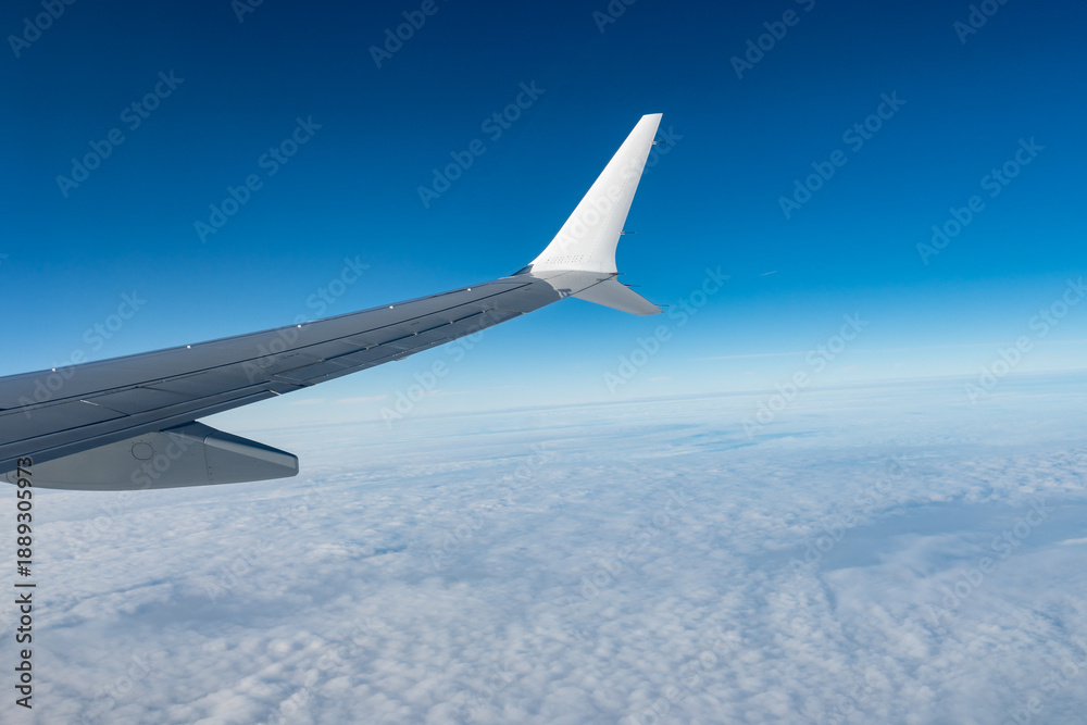 Fototapeta premium Airplane wings extend above white clouds, providing clear view of atmospheric layers and sense of altitude during the flight, air transportation