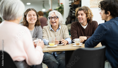Tableau sur toile Family consisting of different generations sits at a large table in a cafe and discusses joint plans and holidays