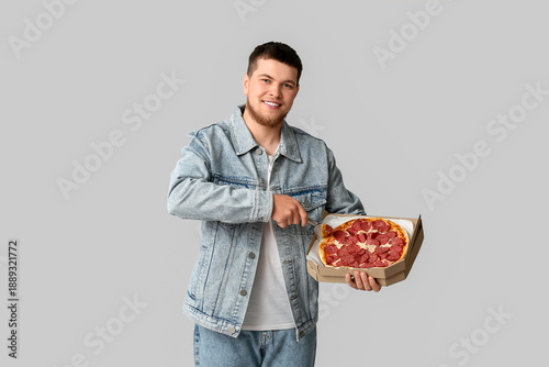 Young man cutting tasty pep...