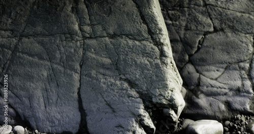 Photos weathered gray coastal rock texture revealing deep fissures and layered strata,